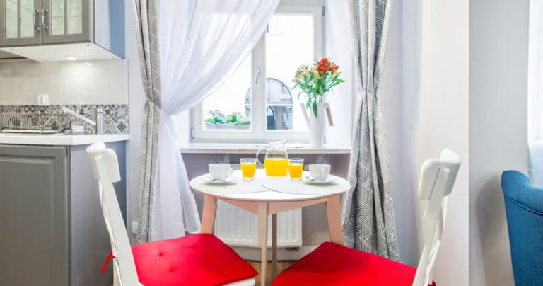 Cozy dining nook by window with two red-cushioned chairs and table set with orange juice